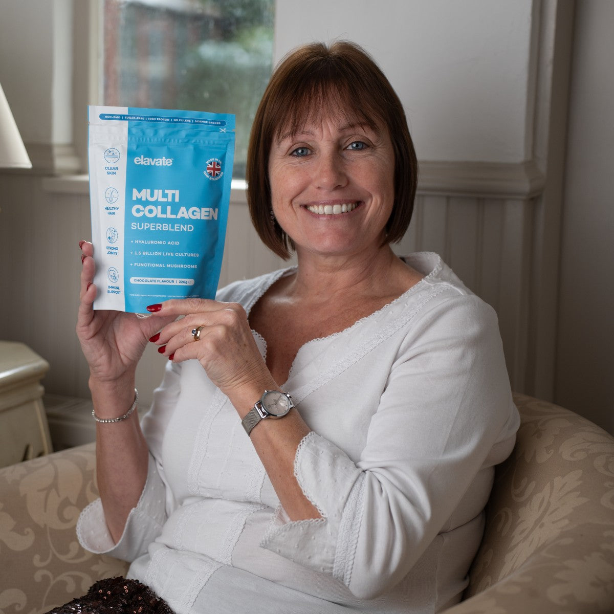 Older female customer holding up a bag of Elavate collagen powder packaging